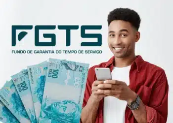 Aniversariantes de maio já têm data para sacar FGTS; confira calendário 6 Jovem de camisa vermelha segura smartphone sorrindo, com notas de R$100 e logotipo do FGTS ao fundo.