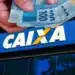 Saque Calamidade é disponibilizado pela CAIXA a moradores de cidades do Pará (PA) 12 Mão segura cédulas de R$ 100 em frente à fachada da Caixa Econômica Federal, banco responsável pelo Saque Calamidade do FGTS