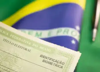 Situação eleitoral: como saber se seu título está apto para votar em 2026 6 Título eleitoral da República Federativa do Brasil com identificação biométrica em primeiro plano e bandeira brasileira ao fundo.