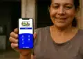 Bolsa Família de maio abre consulta no app; veja quando você recebe 12 Mulher segurando celular com aplicativo do Bolsa Família aberto na tela