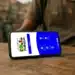 Confira as melhorias no app do Bolsa Família que começam hoje (18) 12 Celular sobre mesa de madeira com a tela do aplicativo Bolsa Família