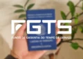 Adeus dívida no cartão: Governo libera até R$ 1.000 do FGTS para quitar débitos e limpar nome em maio 12 Pessoa segura carteira de trabalho com destaque para o logo do FGTS