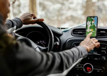Motorista ao volante toca a tela de um celular com aplicativo de mapa