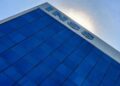 Letreiro do INSS no alto de um prédio de fachada azul e, ao redor, o céu claro ao fundo