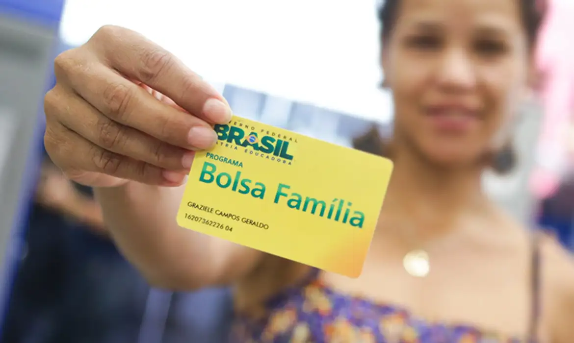 Caixa paga Bolsa Família de julho entre os dias 20 e 31: veja quando cai pelo seu NIS 2 Mulher segura e mostra cartão amarelo do programa Bolsa Família com nome visível