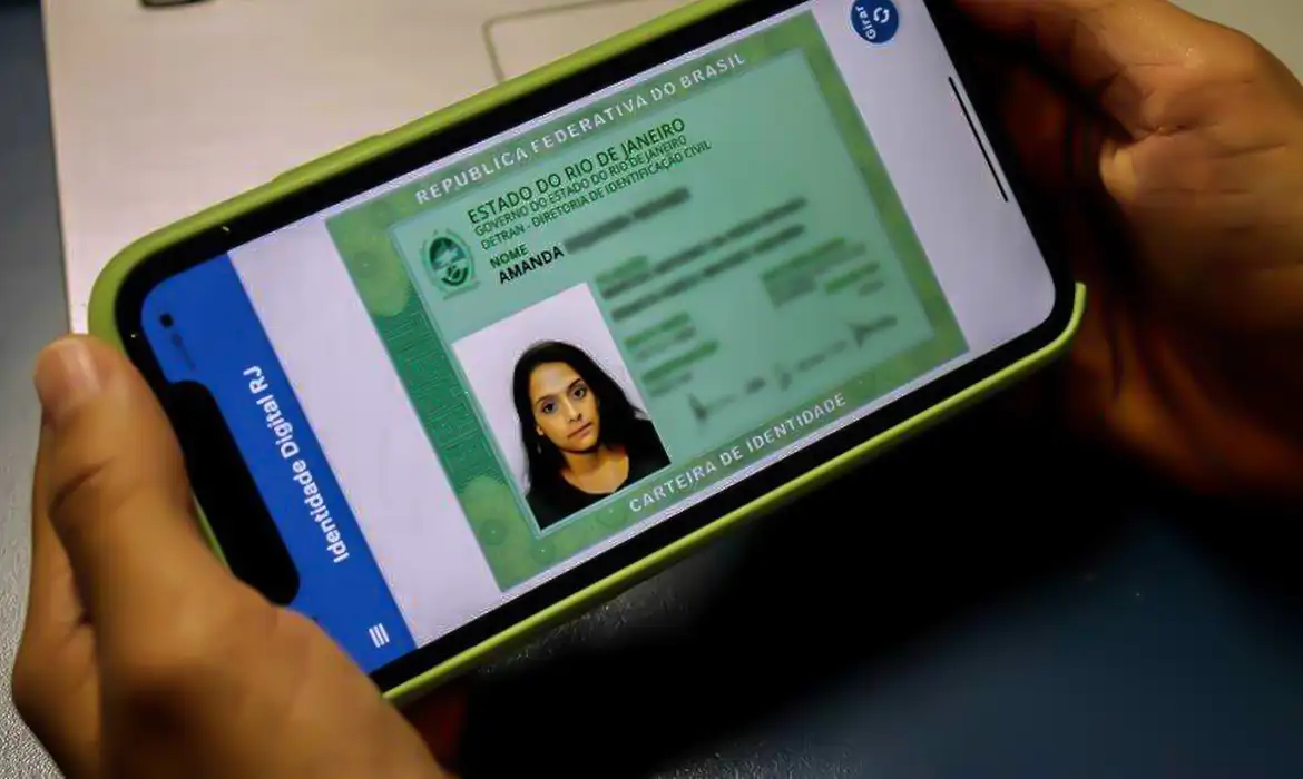 Governo envia alertas no WhatsApp para 55,8 milhões que emitiram CIN, mas não baixaram versão digital 2 Cartão de identidade digital do Rio de Janeiro mostrado em smartphone por mãos adultas