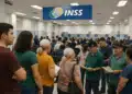 Perícias médicas do INSS no Sertão pernambucano serão antecipadas; veja datas 12 Pessoas em fila dentro de agência do INSS, sob placa azul com logotipo, aguardando atendimento com documentos nas mãos.