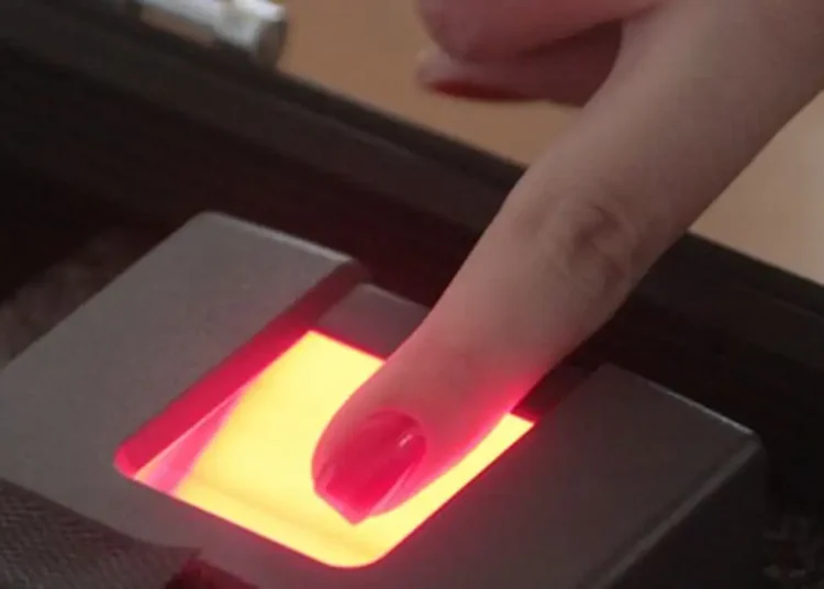 Quem recebe INSS terá que fazer biometria? Entenda as novas regras 2 Dedo com unha vermelha posicionado sobre leitor biométrico digital com luz amarela e vermelha durante coleta de impressão