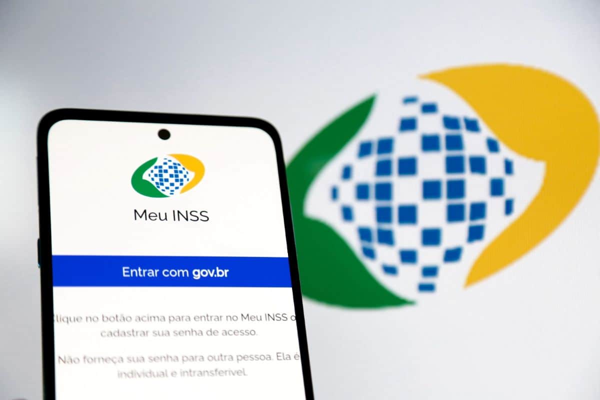 Aposentados e pensionistas sem atendimento presencial: INSS fecha 4 dias seguidos e libera apenas 'Meu INSS' e 135 2 Celular exibe tela de login do Meu INSS com logo do INSS ampliado ao fundo