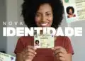Adeus, RG antigo: mutirão realiza nova rodada para emissão da Carteira de Identidade Nacional nesta semana 12 Mulher sorridente segura nova carteira de identidade brasileira com destaque para o documento e fundo claro