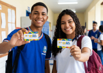 Dois jovens estudantes uniformizados mostram cartões do programa Pé-de-Meia em corredor de escola